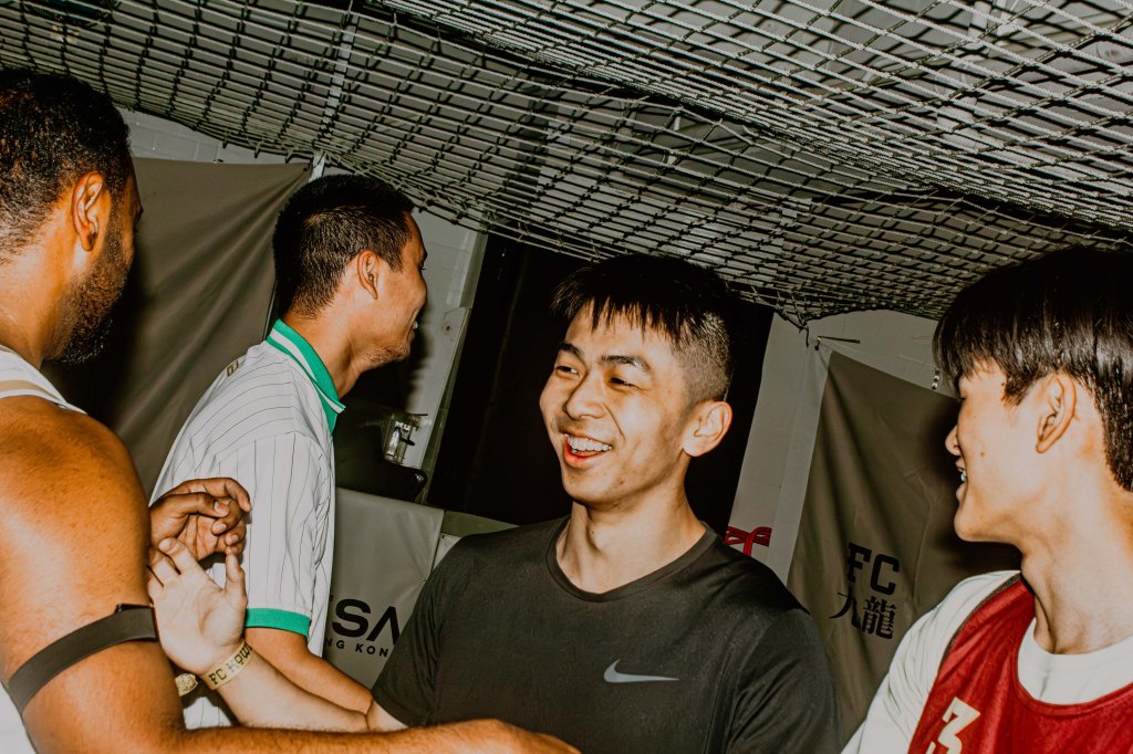 Group of four young men smiling and interacting in a sports environment.
